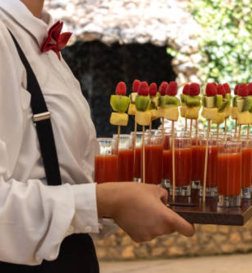 unrecognizable waiter carrying a wooden tray with fruit cocktail canapés at an event celebration